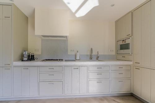 a white kitchen with white cabinets and a microwave at Duynzoom 5 in De Koog