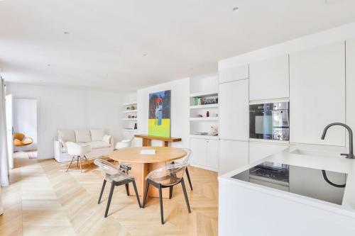 - une cuisine blanche avec une table et des chaises en bois dans l'établissement Le petit palais de L'Élysée, à Paris