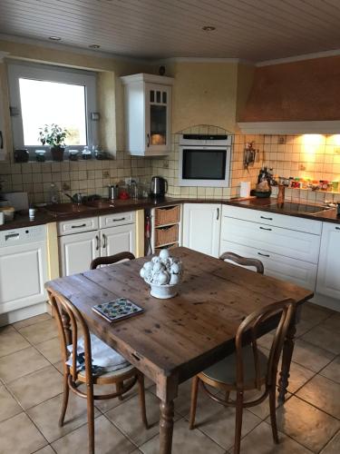 une cuisine avec une table en bois et des chaises dans l'établissement La Guillerette, authentique longère bretonne, à Bannalec