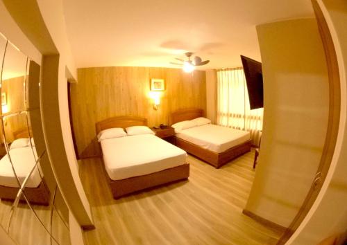 Habitación de hotel con 2 camas y espejo en Hotel Asturias Inn en Lima