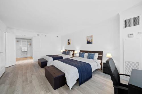 a white bedroom with two beds and a television at CozySuites Showboat 1BR 2BA OceanFront Villa in Atlantic City