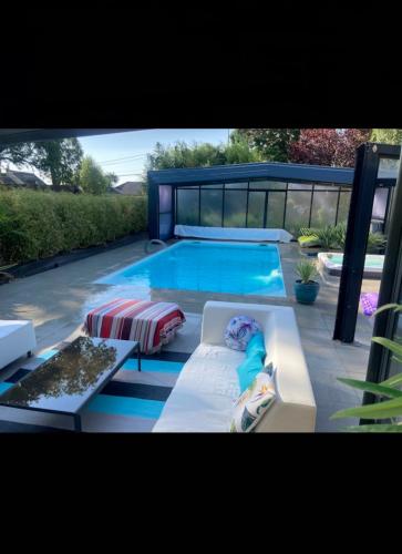 - une piscine avec un canapé et une chaise longue dans l'établissement La Villa Séquoia, à Les Bordes-Aumont