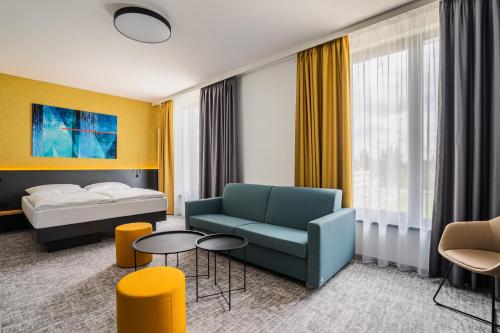 フラデツ・クラーロヴェーにあるEA Congress Hotel Aldisのベッド、ソファ、テーブルが備わるホテルルームです。