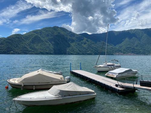 3 Boote sind an einem Dock im Wasser angedockt. in der Unterkunft Life is Good - Front Lake Apartment in Villa in Tremezzo
