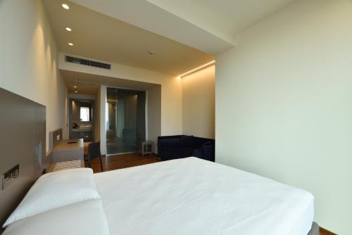 ein Schlafzimmer mit einem weißen Bett und ein Wohnzimmer in der Unterkunft Hotel Le Roi in Varraze