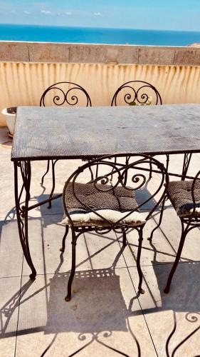 a wooden table with two chairs and a bench at RooftopTerrace apartment in village center in Cargèse