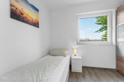a white bedroom with a bed and a window at Niewoh Ferienhaus Wiesenblick,Ammerland, Conneforde in Wiefelstede