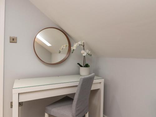 a white desk with a mirror and a vase with flowers at The bungalow at 46 Church St in Chorley