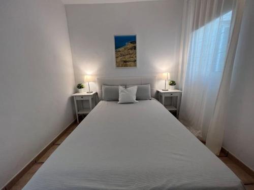 - un grand lit blanc dans une chambre blanche avec deux tables dans l'établissement Casa Macken con piscina climatizada y jacuzzi, à San Bartolomé