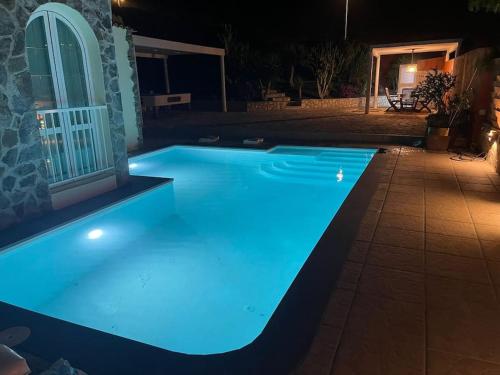 - une piscine éclairée la nuit avec des lumières bleues dans l'établissement Casa Macken con piscina climatizada y jacuzzi, à San Bartolomé