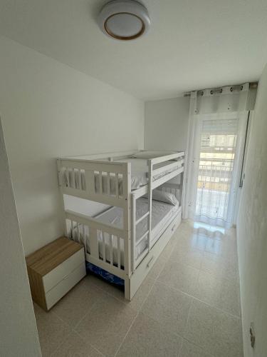 a white room with two bunk beds and a window at Apartamento caribe in Oropesa del Mar