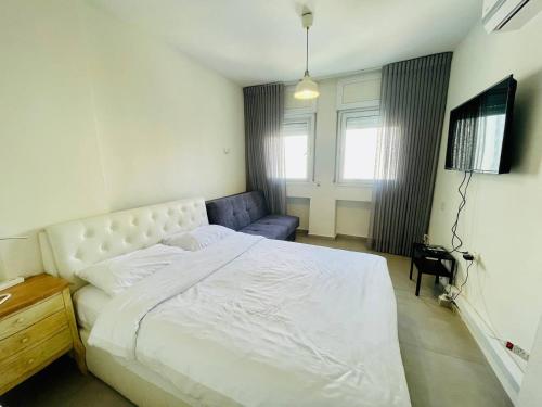 a bedroom with a white bed and a couch at Netanya Sea Studio in Netanya