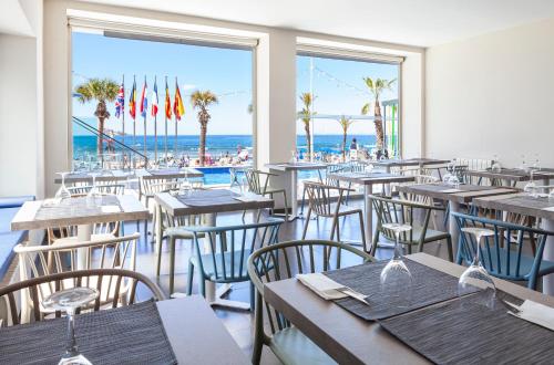 Hotel Brisa في بنيدورم: مطعم به طاولات وكراسي والشاطئ