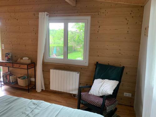 a bedroom with a bed and a window and a chair at Chalet de la Baume in La Châtelaine