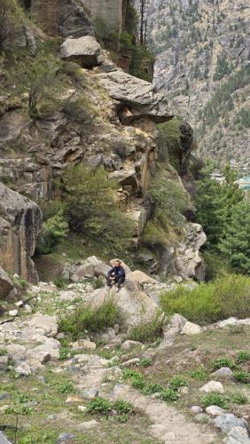 a person is sitting on a rocky mountain at Sangla Valley Camping in Saturang