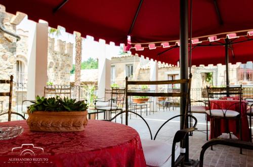 a patio with a red table and chairs and an umbrella at Residenza L'Antico Borgo Hotel in Filadelfia