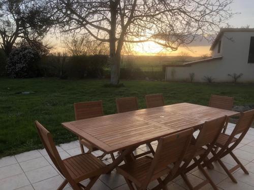 a wooden table and chairs with the sunset in the background at Domaine de la RIMBERTIÈRE in Thuré