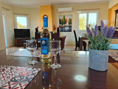 Pazinos/Neveli Cottage في Galangádhos: زجاجة من النبيذ موضوعة على طاولة مع كأسين من النبيذ