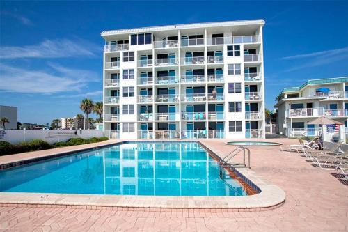 un grande edificio con piscina di fronte a un edificio di SeaBliss, oceanfront 1st floor cozy condo a Daytona Beach