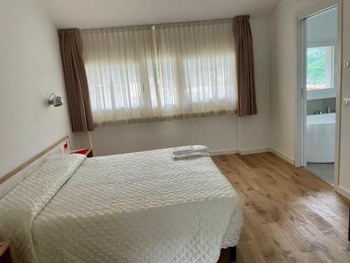 a bedroom with a white bed and a window at Hotel Giardino in Breno