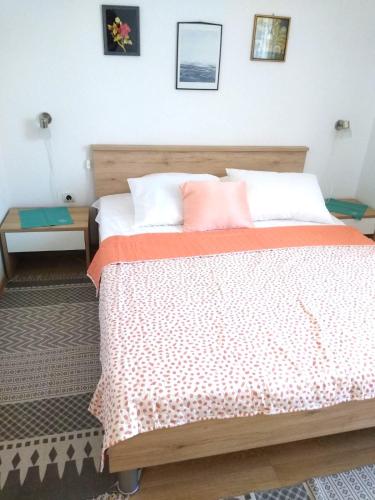 a bedroom with a bed with a orange and white bedspread at Ivago Apartments Sabunike in Privlaka