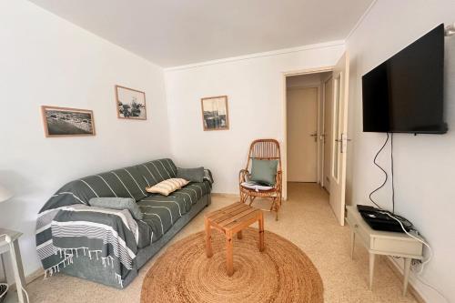 un salon avec un canapé et une télévision à écran plat dans l'établissement L'ANCRE MARINE - Appartement 2 chambres avec parking proche de la plage, au Grau-du-Roi