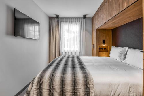 une chambre avec un grand lit blanc et une fenêtre dans l'établissement Kristal, à Megève