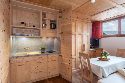 a kitchen with wooden cabinets and a table with a sink at Luxury and Nature House Moarlhof in Castelrotto