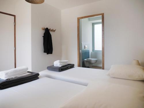 two beds in a white room with a mirror at Les Pingouins du Puits in Guissény