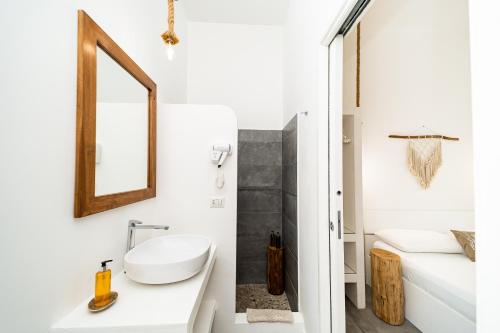 La salle de bains blanche est pourvue d'un lavabo et d'un miroir. dans l'établissement Salento Boutique Room B&B, à Sant'Isidoro