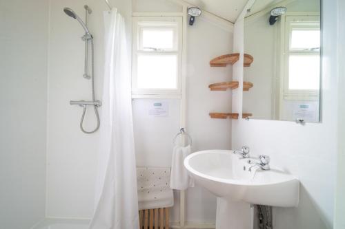 a white bathroom with a sink and a mirror at Skylark - Sweffling Hall in Rendham