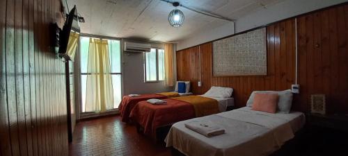 a hotel room with two beds and a television at Nuevo Residencial Uno in Puerto Iguazú
