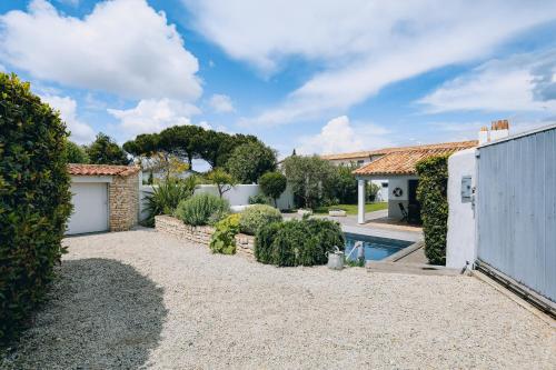 une cour arrière avec une piscine et une maison dans l'établissement Villa Cote Ouest, à La Flotte