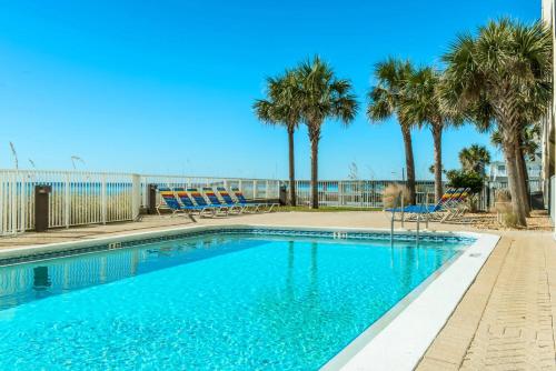 a swimming pool with palm trees and chairs at Ocean Reef 904 by Emerald Coast Retreats in Panama City Beach