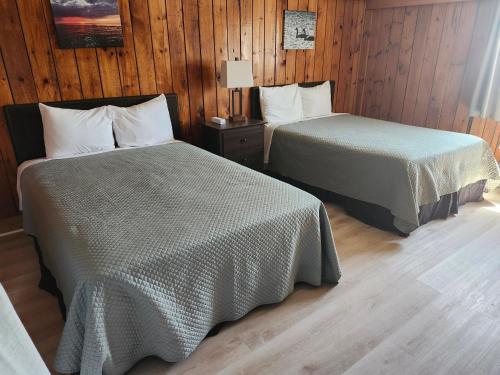 Habitación con 2 camas, paredes de madera y suelo de madera. en The Cove Motel & Restaurant, en Aulds Cove