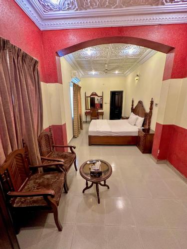 a hotel room with a bed and a table and chairs at Hotel Shelton Palace in Multan