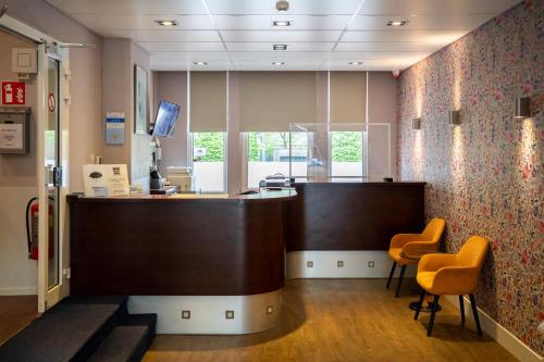 an office with a reception desk and two chairs at Aadam Hotel Wilhelmina in Amsterdam