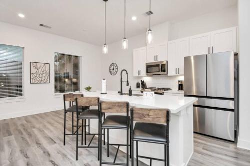 a kitchen with white cabinets and a kitchen island with bar stools at Stylish 4 Beds - Min to Downtown With Backyard in Houston