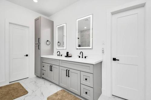 a white bathroom with a sink and two mirrors at Stylish 4 Beds - Min to Downtown With Backyard in Houston