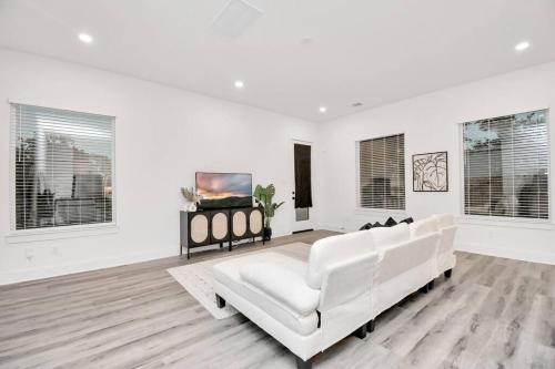 a white living room with a white couch and windows at Stylish 4 Beds - Min to Downtown With Backyard in Houston