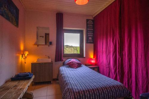 um quarto com uma cama e uma janela com cortinas cor-de-rosa em The Little Paradise Naturist only em Morville
