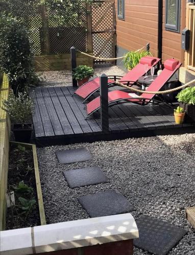 a patio with red chairs on a black deck at Hollicarrs - Wildflower Lodge in York
