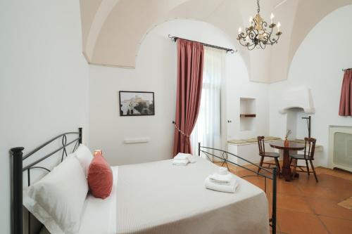a bedroom with a white bed and a table at Masseria Borgo Santuri in Ostuni