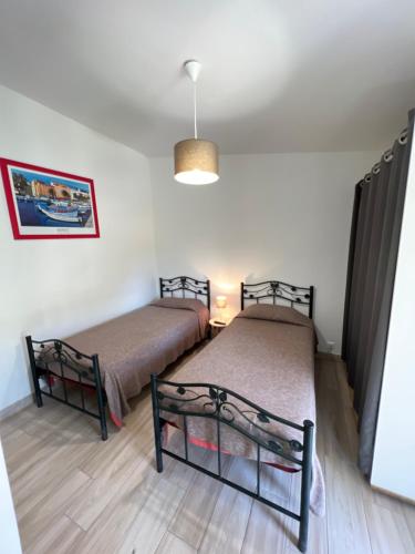 two beds in a room with white walls and wooden floors at Hôtel les jardins de Sta Giulia avec piscine in Porto-Vecchio