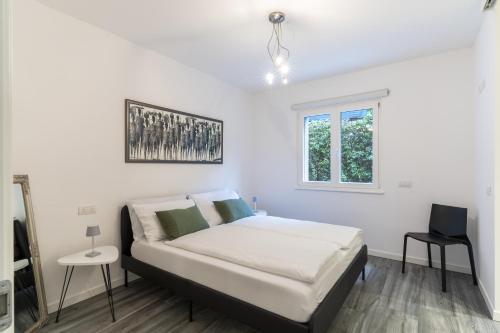 a white bedroom with a bed and a window at Residenza The Rock in Nago-Torbole