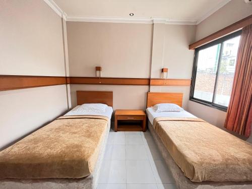 two beds in a room with two windows at Hotel Caravan Tanah Abang in Jakarta