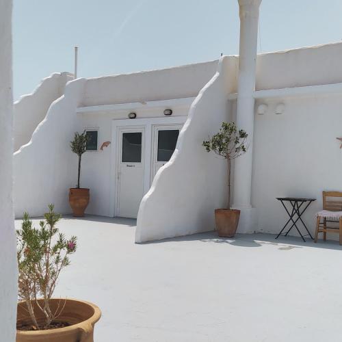 a white building with two potted trees in front of it at BY THE SEA ROOMS, AVLAKI in Porto Rafti