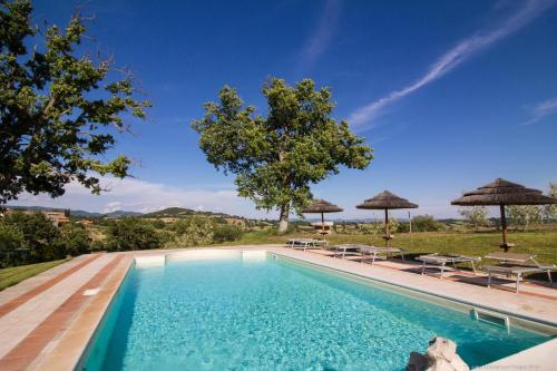 een zwembad met stoelen en parasols bij Country House Poggio Aione in Catabbio