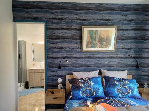 ein Schlafzimmer mit einer blauen Wand und einem Bett mit blauen Kissen in der Unterkunft La maison entre deux plages,vue sur mer classée 4 étoiles in Criel-sur-Mer