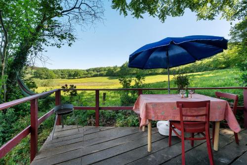 a table with a blue umbrella on a wooden deck at Ferien Tinyhaus im Tale in Ascheffel